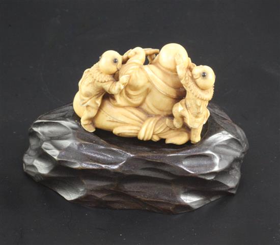 A Japanese ivory okimono of Hotei and three boys, signed Ikkosai, Meiji period, 4.6cm, wood stand